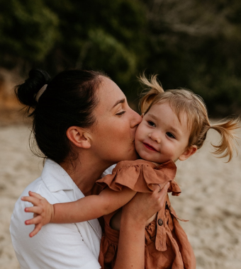 woman holding and kissing small child on cheek