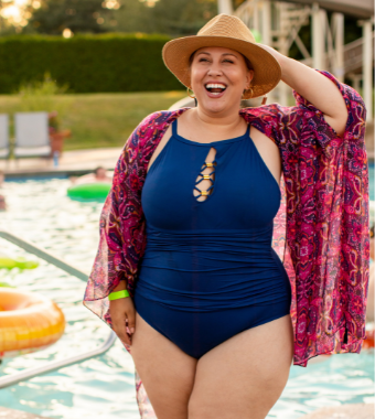 Larger bodied woman in blue bathing suit standing in front of pool smiling