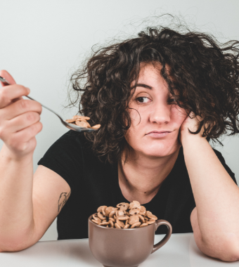 Woman looking sad eating cereal